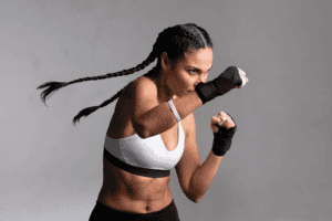 Image of a fit woman with braids and a white sports bra doing martial arts. Blog named "Protein 101 - All About Protein For Optimal Healing and Health" by tonika health (https://tonikahealth.com.au)